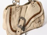 beige leather handbag with metal buckles on a white background