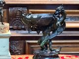 une statue représentant un homme et une femme, posée sur une table à côté d'un vase