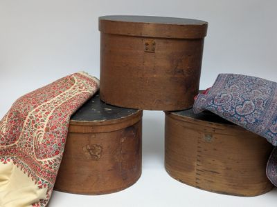 trois boîtes en bois ornées de rubans, disposées les unes à côté des autres