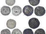 a close up of a bunch of silver coins on a white surface
