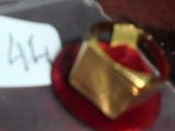 une bague en or posée sur une assiette rouge, avec une étiquette de prix