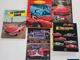 four ferrari books on a white table with a red car in the background