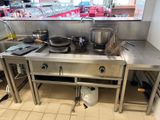 un plan de travail en acier inoxydable sur lequel sont posés des casseroles et des poêles, dans une cuisine professionnelle