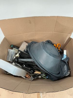 une boîte en carton remplie d'objets hétéroclites sur le sol
