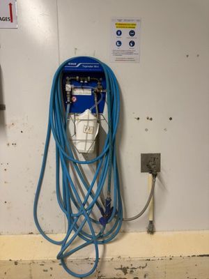 un tuyau bleu fixé au mur, à côté d'une prise électrique