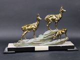 sculpture en bronze représentant trois cerfs sur un rocher, avec un socle noir