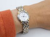 wrist shot of a woman wearing a silver and gold watch on her wrist