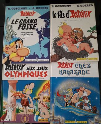 Quatre albums de bandes dessinées sont empilés les uns sur les autres sur une table
