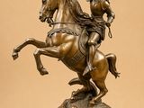 bronze statue of a man on a horse with a flag on its back