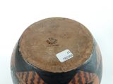a black and orange vase with a label on it