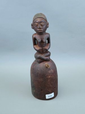 une vieille statue en bois représentant un homme assis au sommet d'une cloche