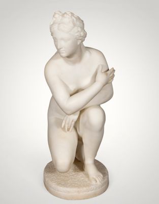 a white marble statue of a boy kneeling on a pedestal