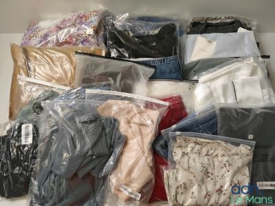 de nombreux types de vêtements différents, rangés dans des sacs sur une étagère