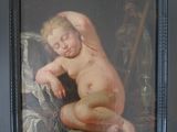 tableau représentant un enfant nu, dans un cadre noir, posé sur une table