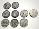 six types différents de pièces d'argent sont disposés sur une surface blanche