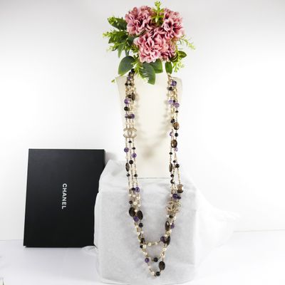 purple and black beaded necklace with flowers in a white vase