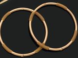pair of gold hoop earrings on a black surface next to a pair of scissors