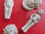 four small white figurines of people on a red surface