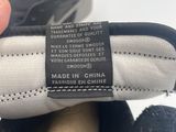 someone is holding a pair of black and white shoes with a label on it