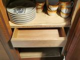 a wooden cabinet with dishes and cups on it