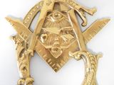 broche représentant une équerre et un compas maçonniques dorés sur fond blanc