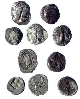 a close up of a group of ancient coins on a white surface