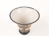a white and black vase sitting on a white surface