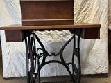 une vieille machine à coudre posée sur une table devant un drap blanc
