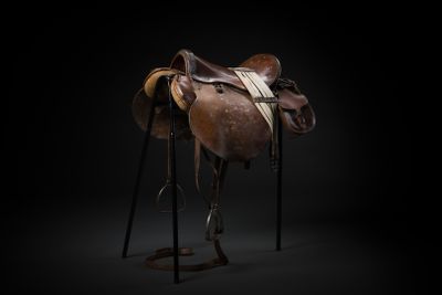 an old saddle on a stand against a black background