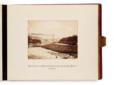 an old photo of a river with a bridge in the background