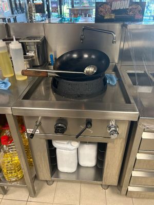 un plan de travail en acier inoxydable sur lequel est posée une poêle, dans une cuisine professionnelle
