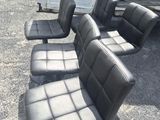 quatre fauteuils en cuir noir posés sur un parking, à côté d'un camion