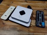 un appareil blanc posé sur une table en bois, à côté d'une télécommande