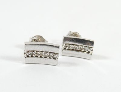 une paire de boucles d'oreilles en argent ornées de diamants, sur fond blanc