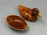 un canard en céramique et un bol posés sur une table