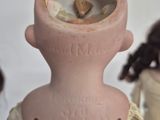 a pink vase with a doll inside of it on a table
