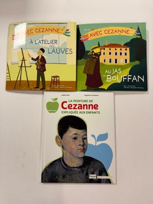 trois livres pour enfants posés sur un mur blanc orné d'un tableau représentant un garçon