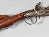a very old gun with a wooden handle and a silver plated muzzle