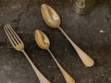 four silver spoons and a silver cup on a table