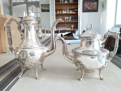 deux théières en argent posées sur une table dans un salon