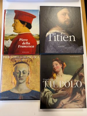 trois livres posés sur une table, avec la photo d'un homme portant un chapeau rouge
