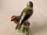 a small figurine of a bird sitting on a branch
