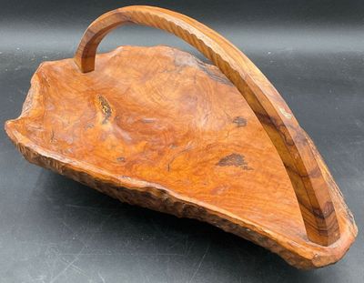 une photo représentant un panier en bois muni d'une anse, posé sur une table
