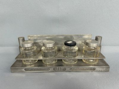 plateau en argent sur lequel sont disposées six flacons de parfum, sur un fond blanc