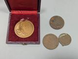 a gold medal in a red box next to some coins