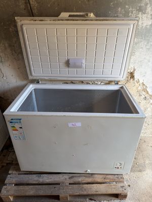 un congélateur coffre blanc posé sur une palette dans une pièce