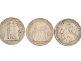 trois types différents de pièces d'argent sur une surface blanche