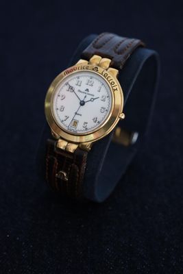 a close up of a watch on a black surface with a dark background