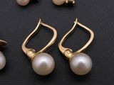 two pairs of pearl earrings and a pair of gold earrings on a black surface