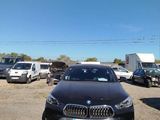 a black bmw car parked in a lot with other cars